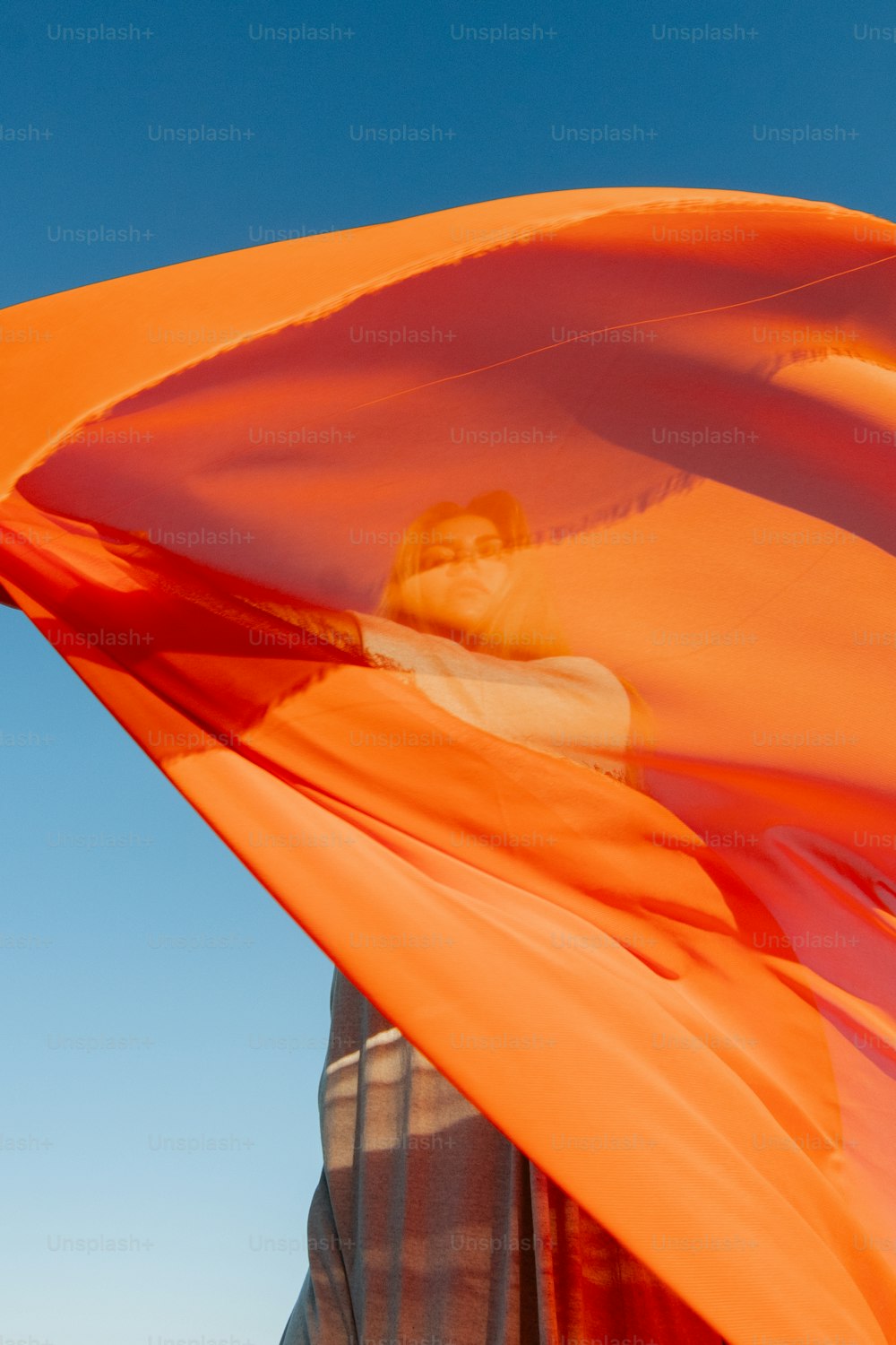 Un hombre sosteniendo una gran cometa naranja en el aire