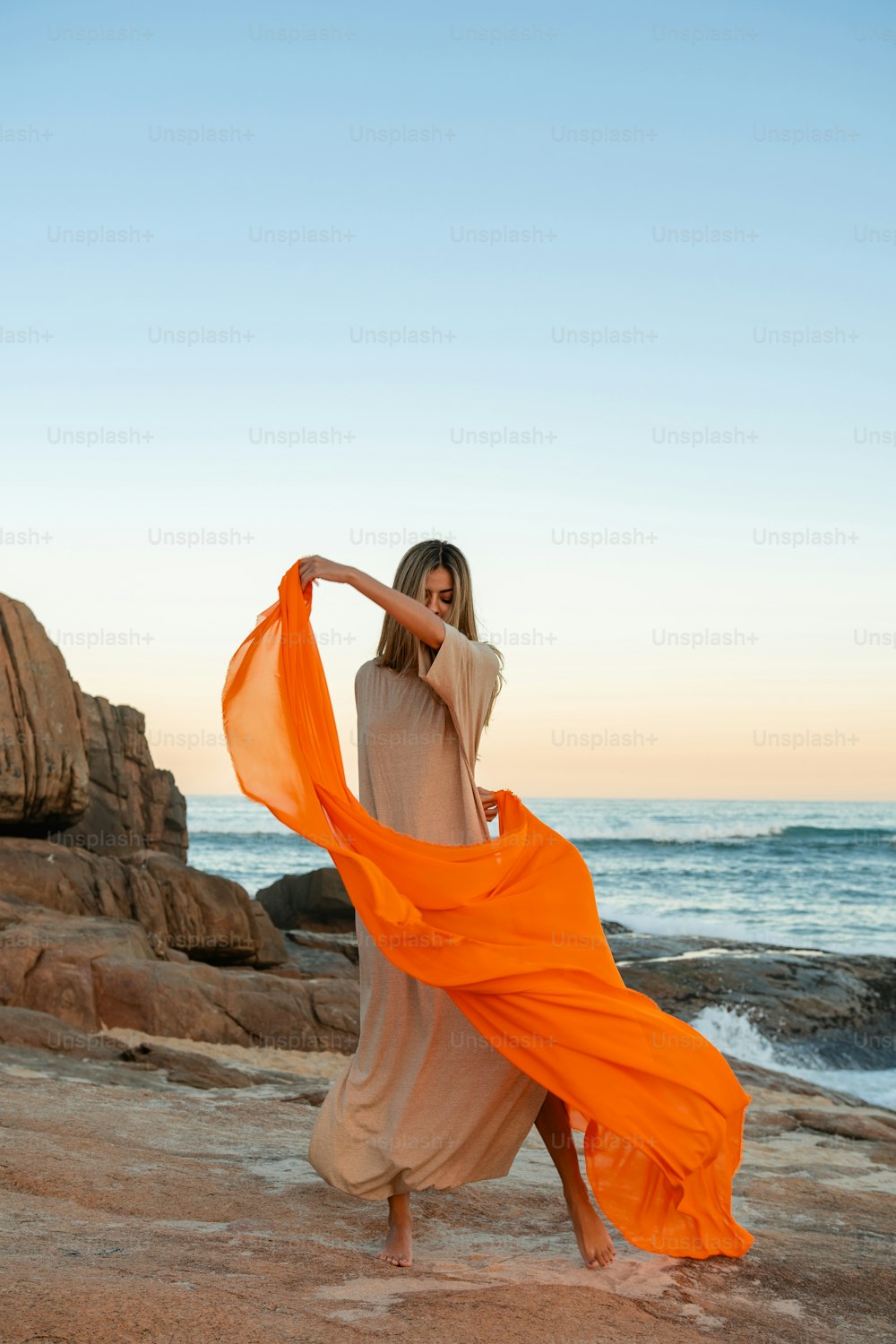 a woman in an orange dress on the beach