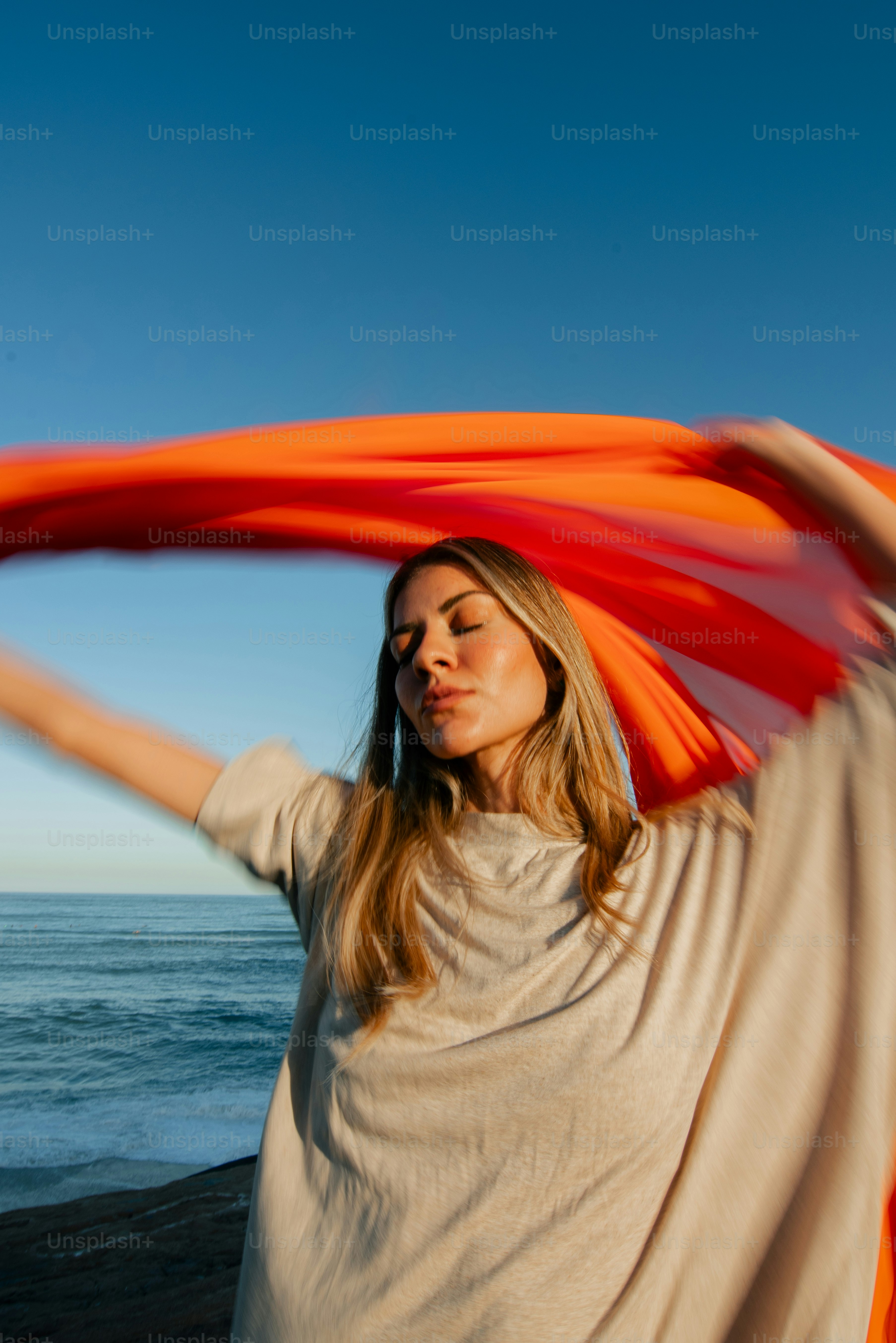 a woman holding an orange scarf over her head