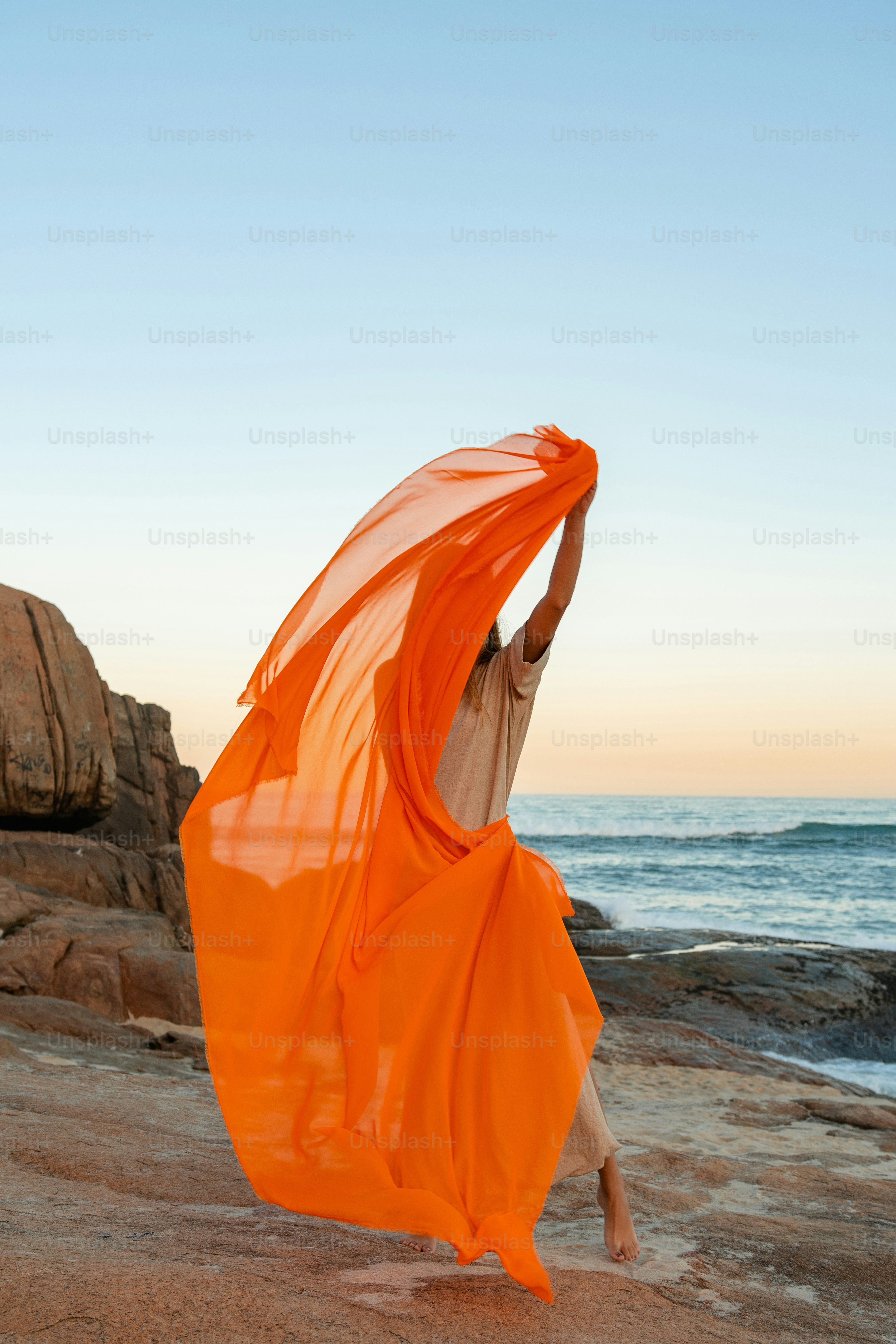 Une femme en robe orange sur la plage