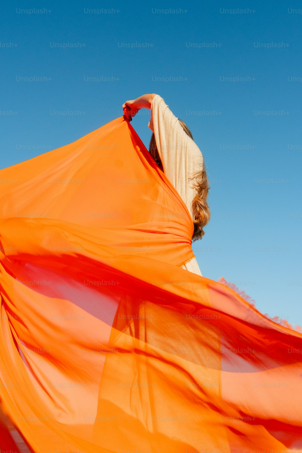 a woman is holding a large orange scarf