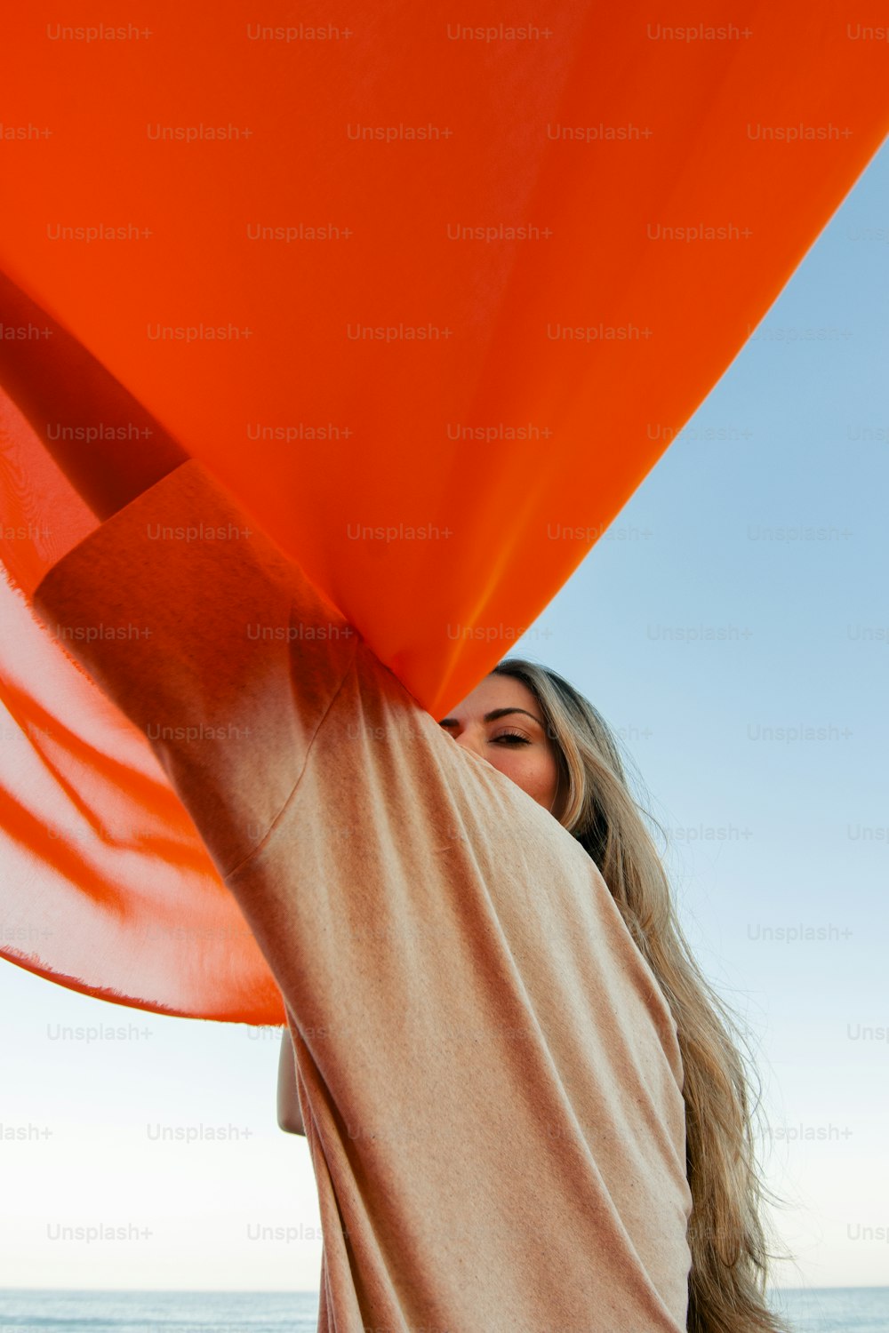 a woman holding a large orange umbrella over her head