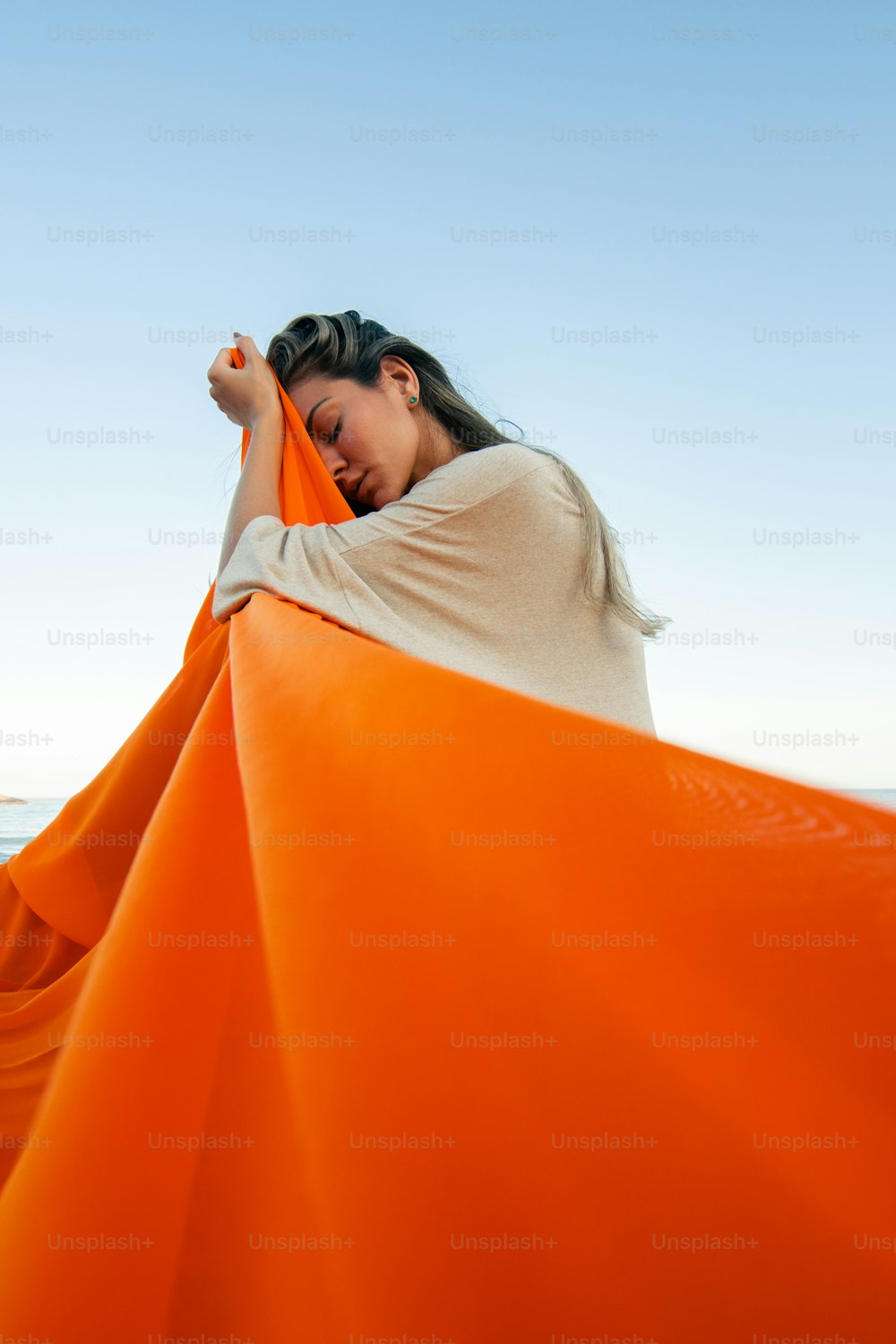 a woman wrapped in an orange sheet on the beach