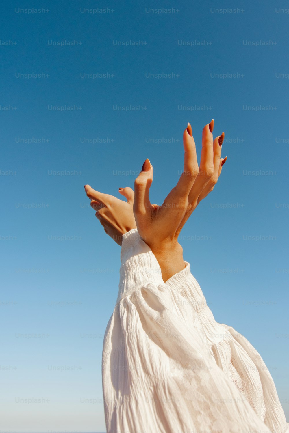 a woman in a white dress with her hands in the air