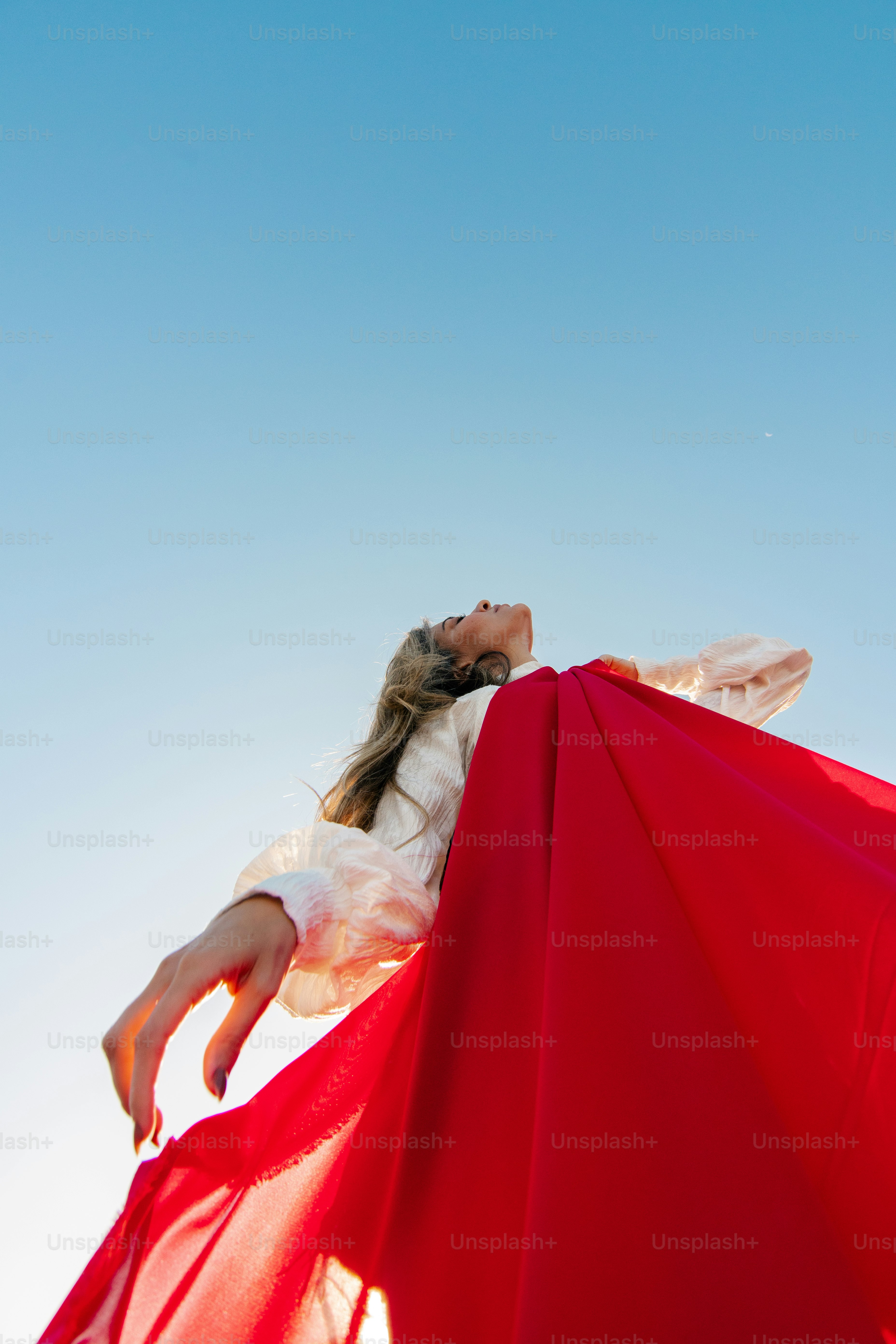 a woman in a white dress holding a red umbrella