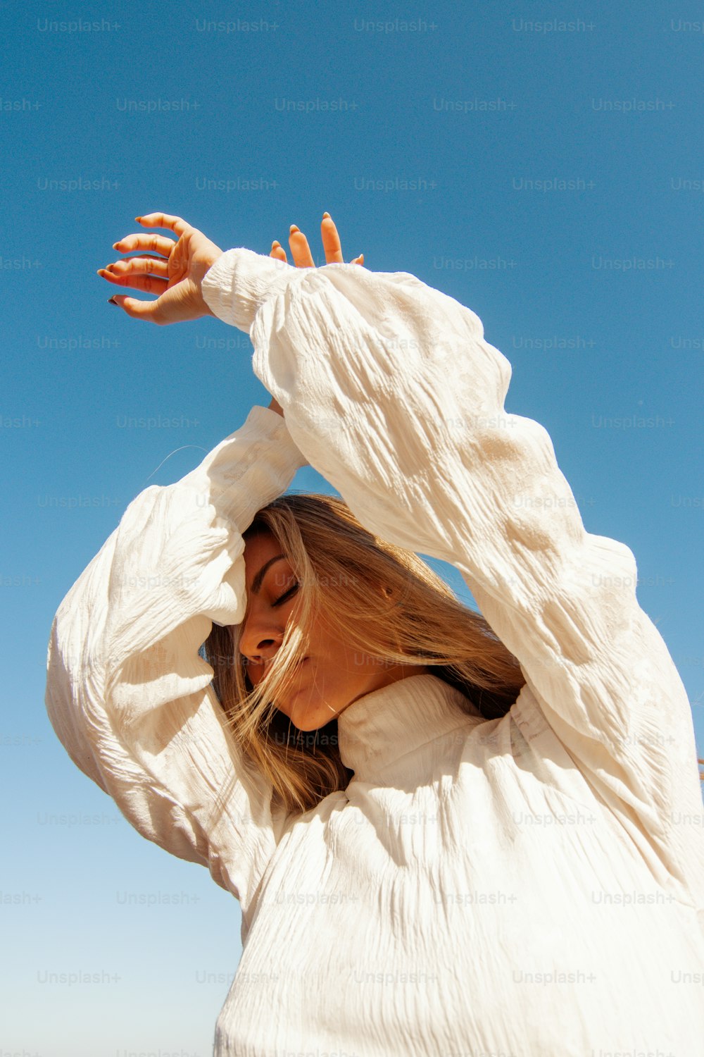 Una donna in una camicia bianca sta facendo volare un aquilone