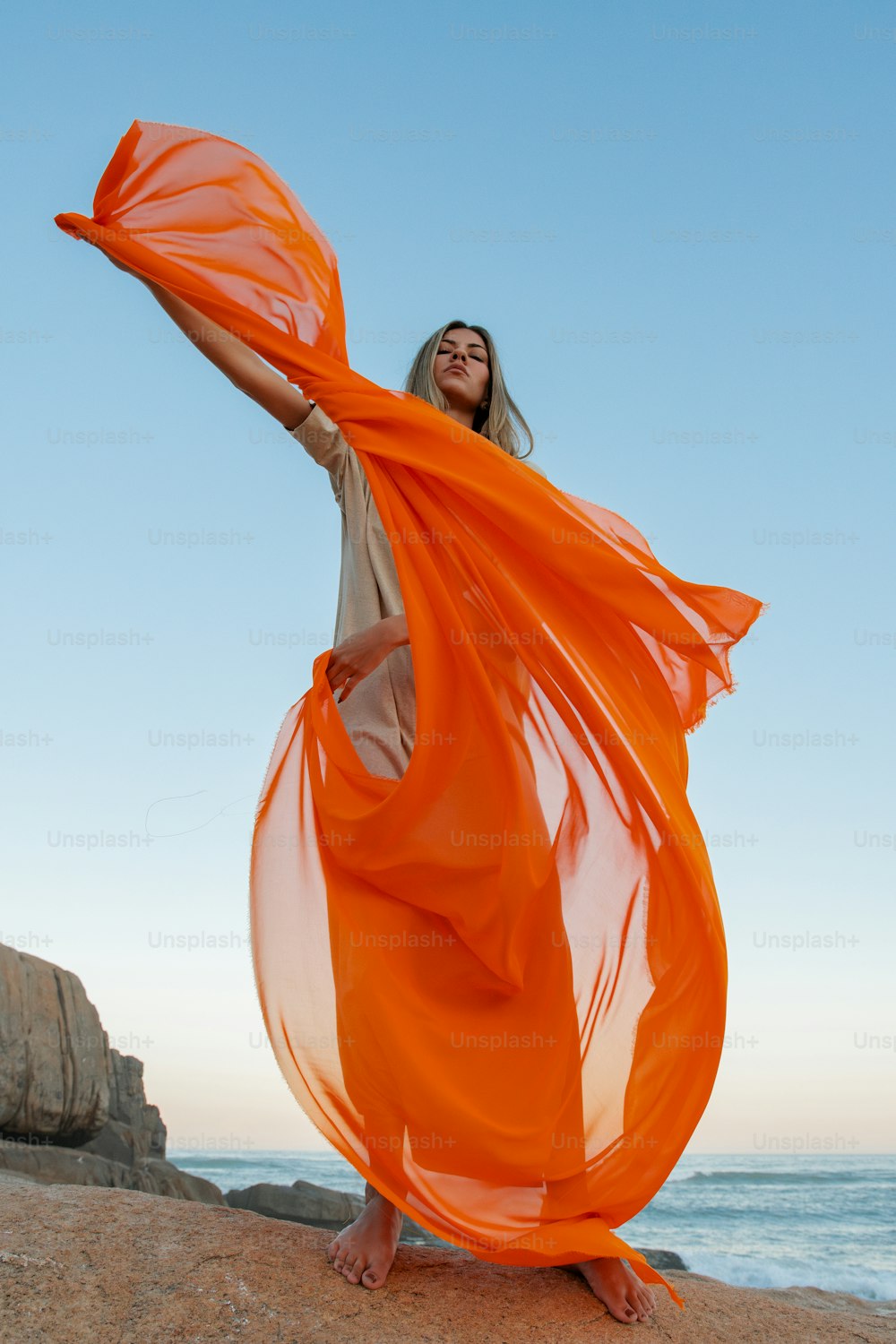 Una donna in un vestito arancione in piedi su una spiaggia