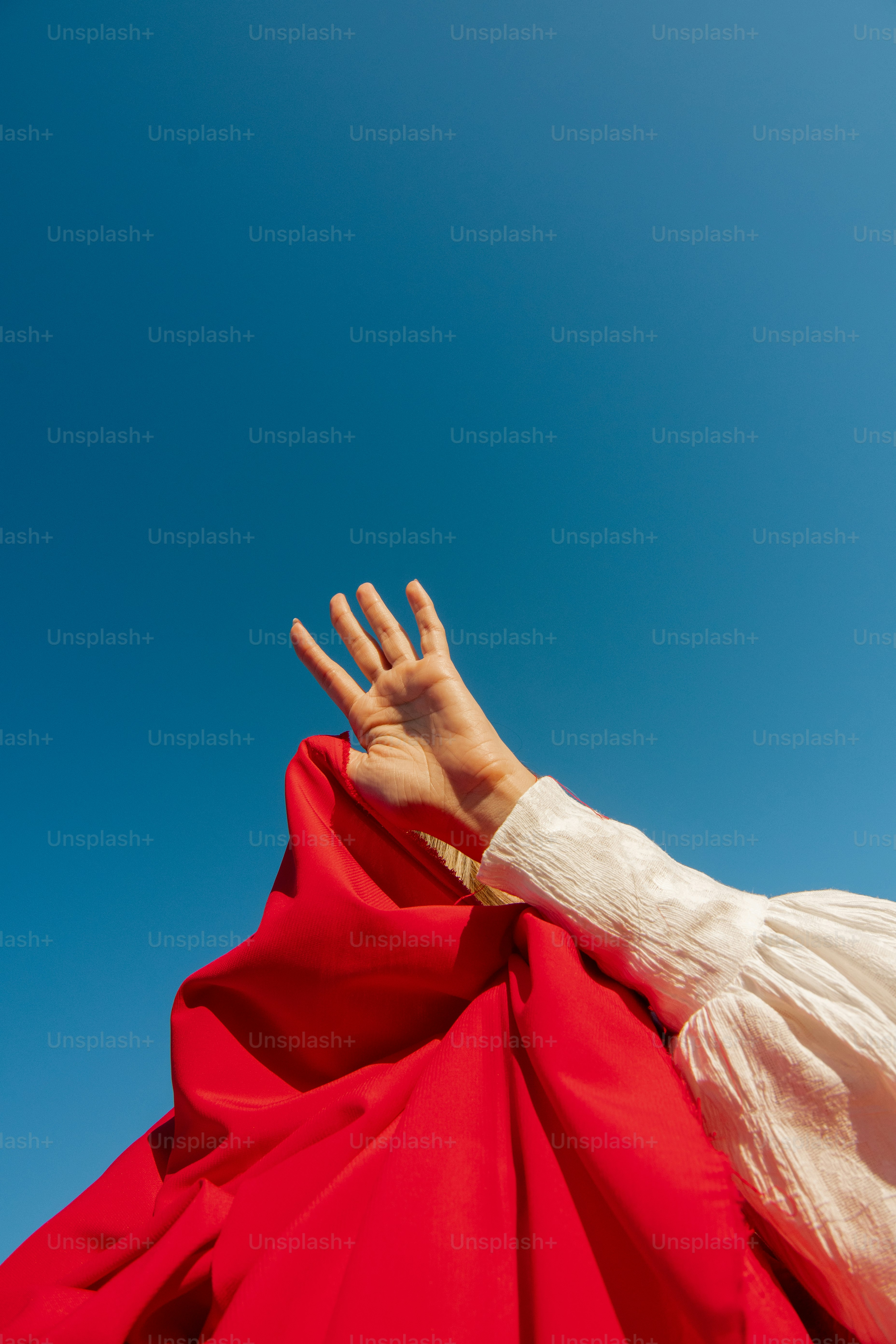 A hand reaching up into a blue sky photo – Red white Image on Unsplash