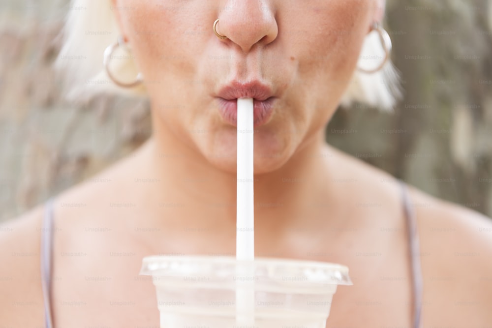 a woman drinking a drink with a straw in her mouth