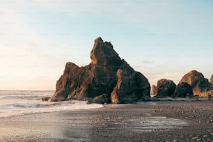 una grande formazione rocciosa seduta sulla cima di una spiaggia sabbiosa