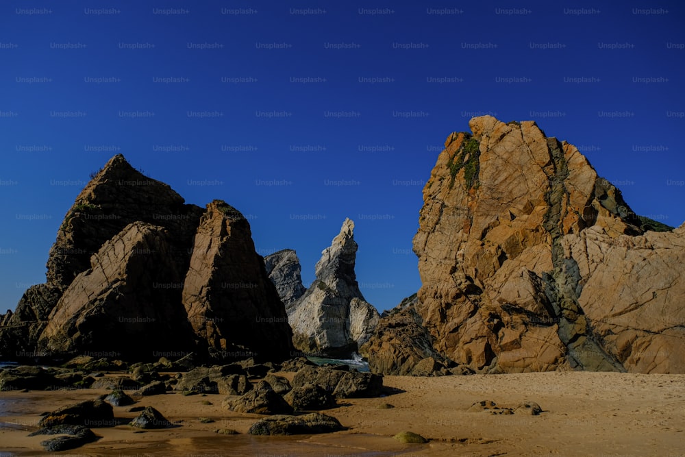 algumas rochas em uma praia com um céu azul no fundo