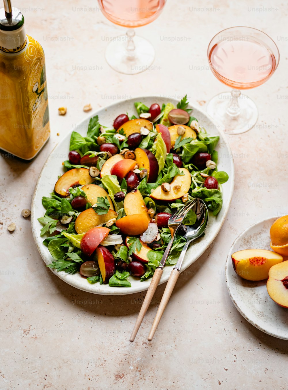 un plato blanco cubierto con una ensalada junto a dos copas de vino