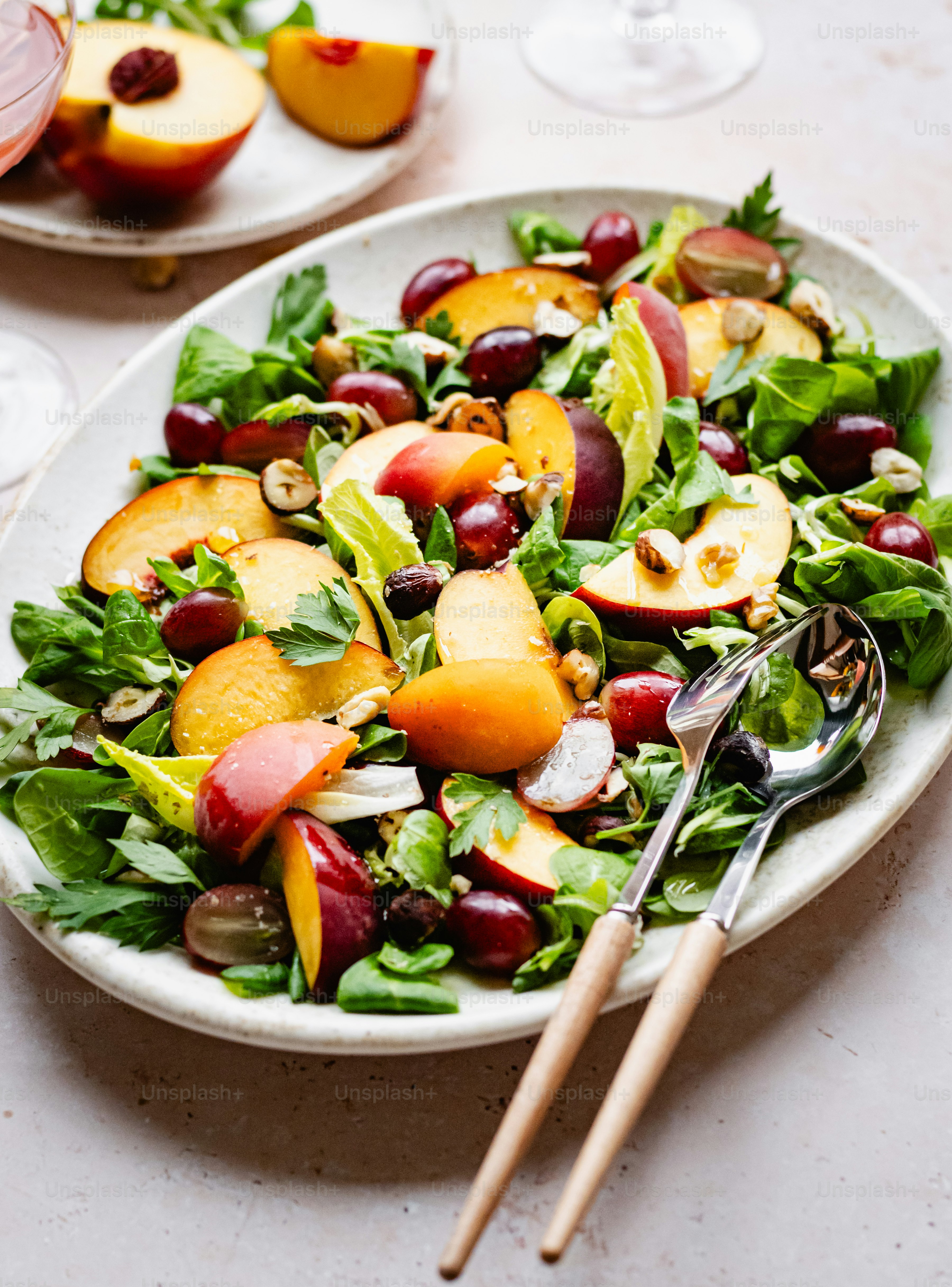 a white plate topped with a salad next to a glass of wine