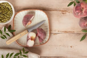 a cutting board topped with sliced up peaches next to a bowl of seeds