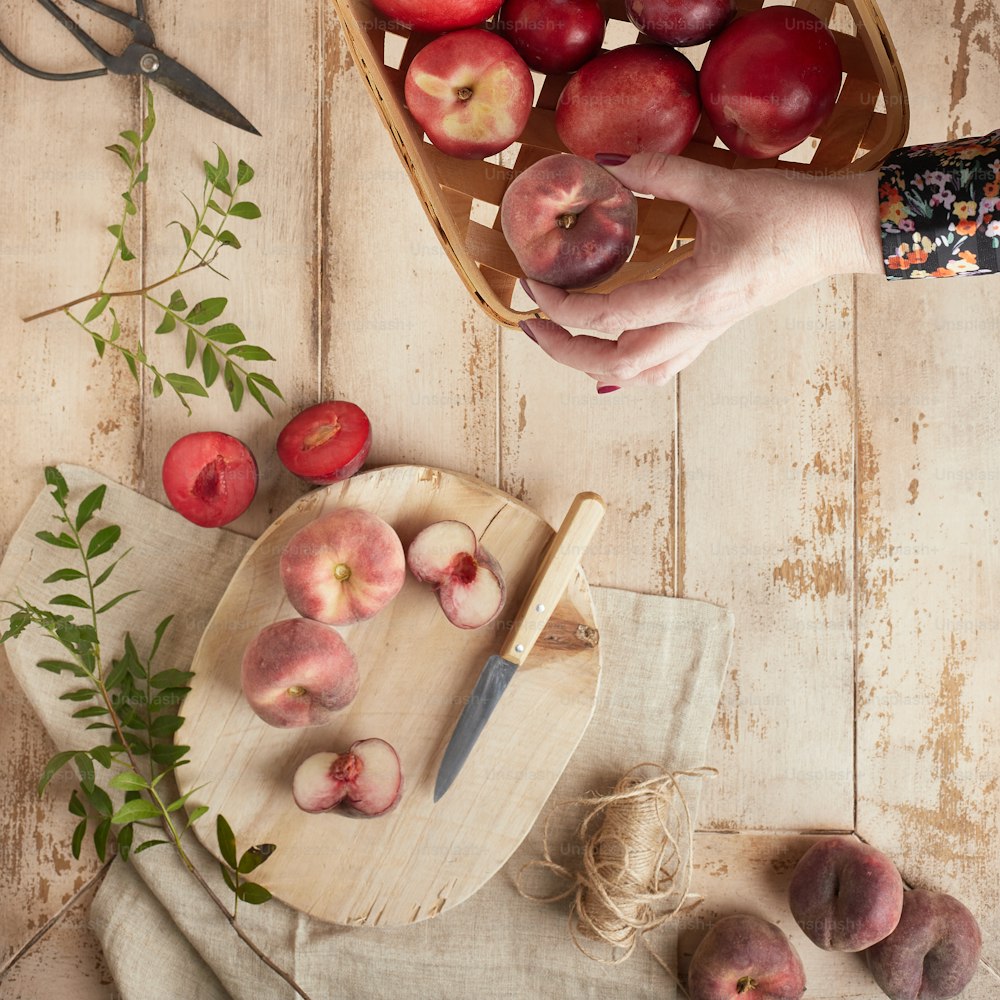 a person holding a basket of peaches on a cutting board