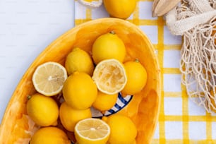 a yellow bowl filled with lemons on top of a table