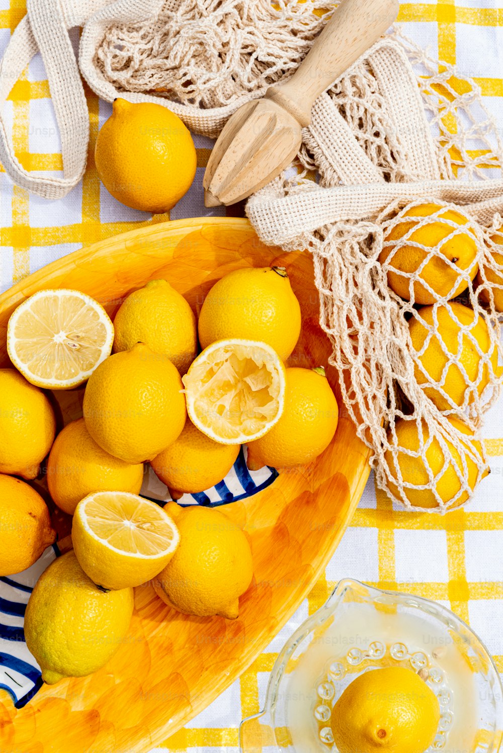 a bowl of lemons on a yellow and white checkered tablecloth