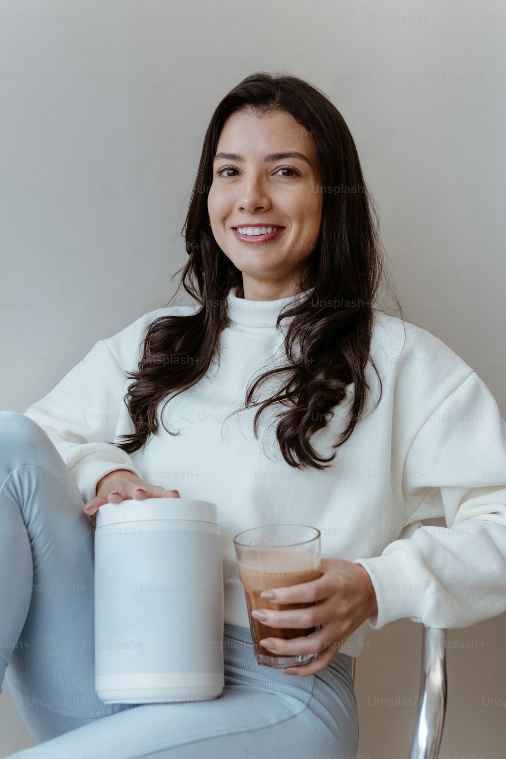 a woman sitting on a chair holding a cup of coffee