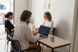 two people sitting at a table with a laptop