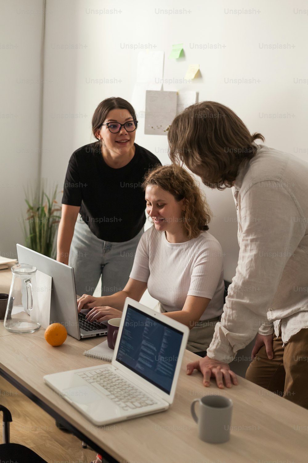 a group of people standing around a table with laptops