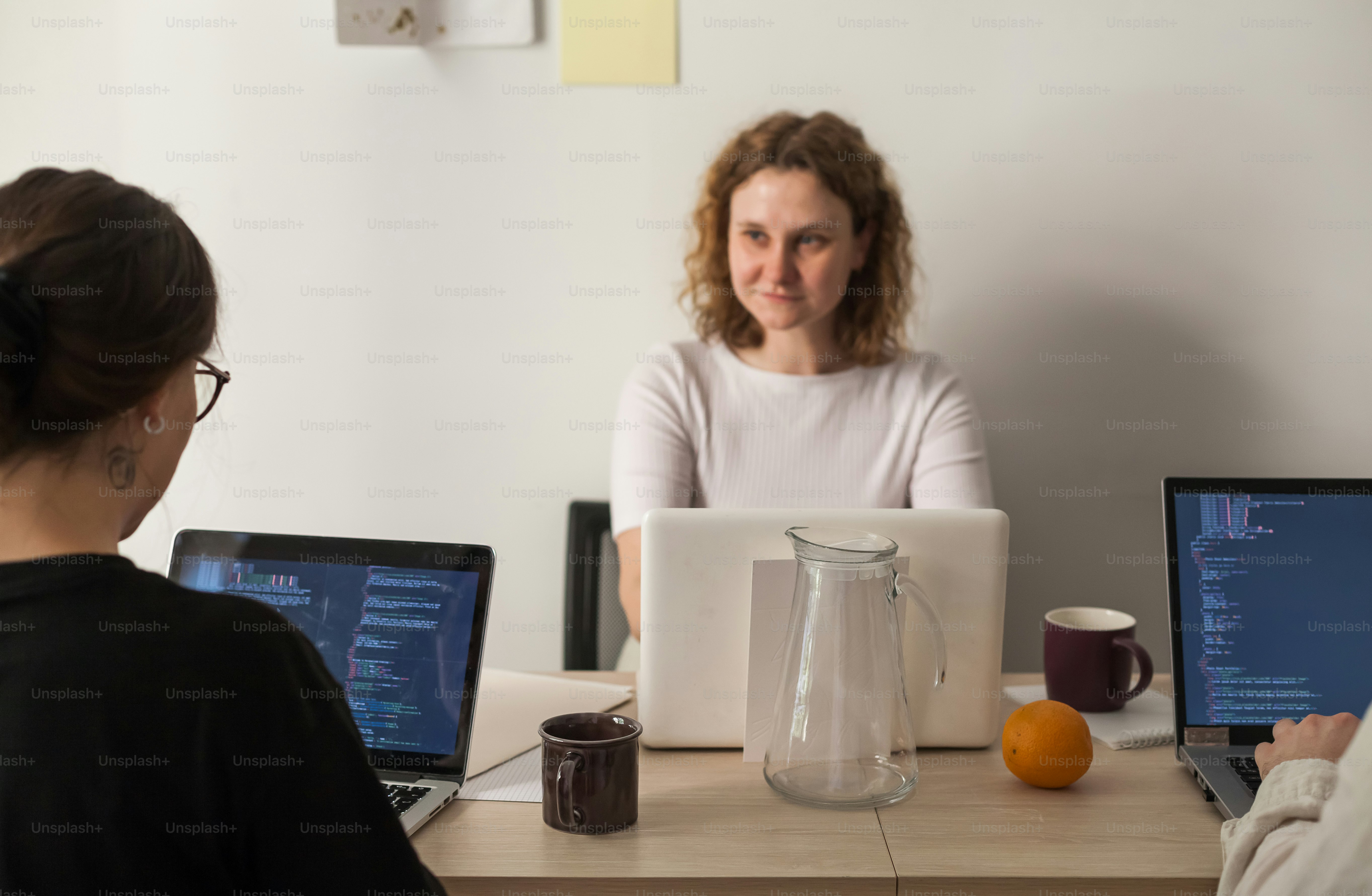 Two women sitting at a table with laptops photo – Business Image on ...