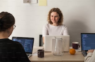 two women sitting at a table with laptops