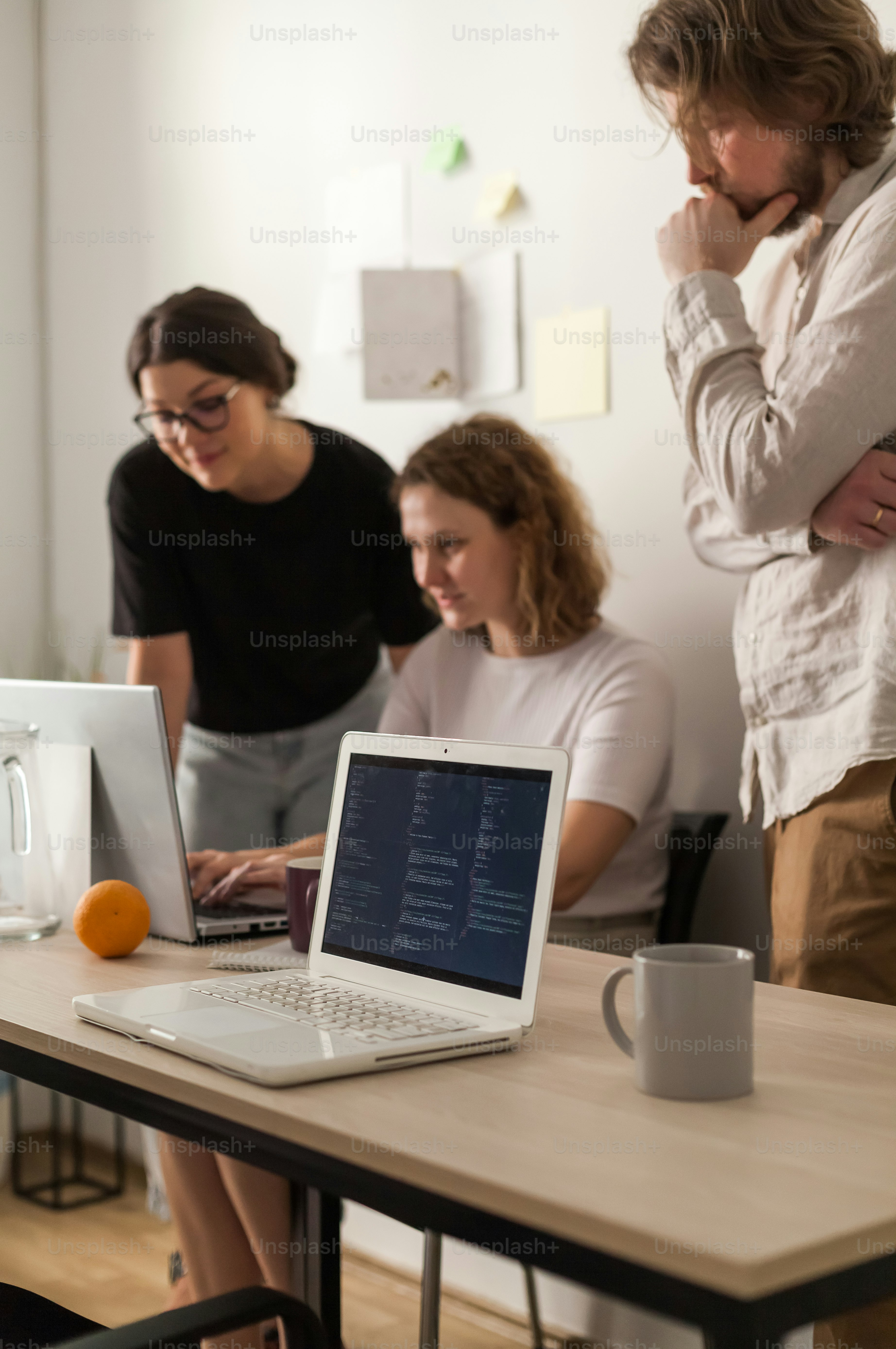 Un gruppo di persone in piedi intorno a un tavolo con computer portatili