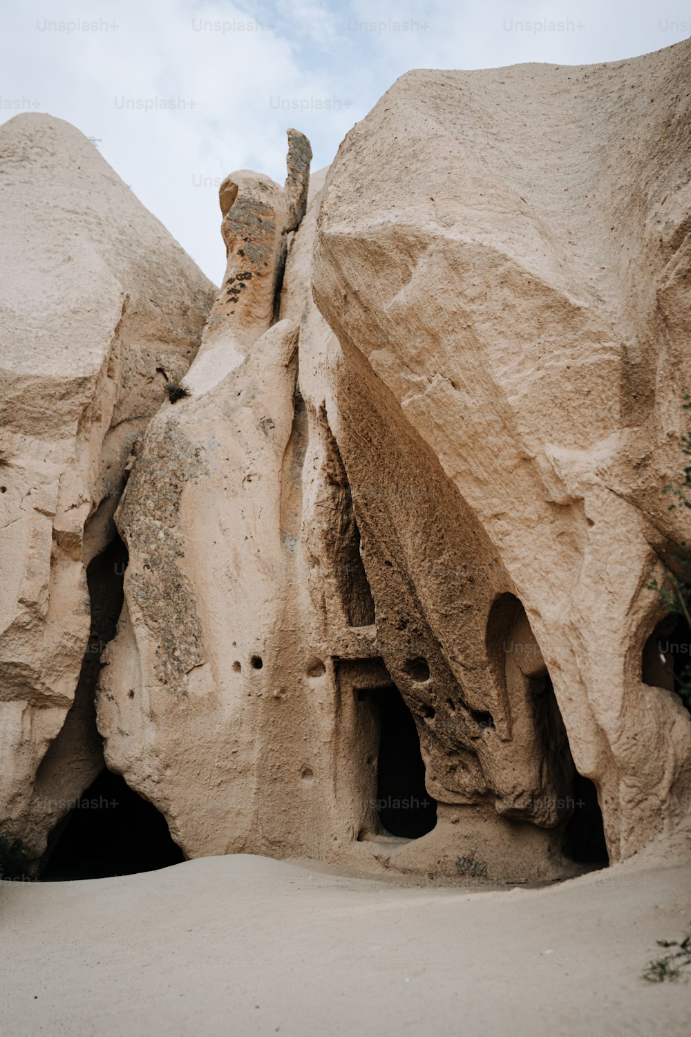 una grande formazione rocciosa con una piccola grotta al suo interno