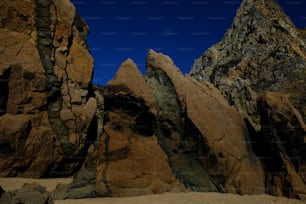 eine Gruppe von Felsen, die auf einem Sandstrand sitzen