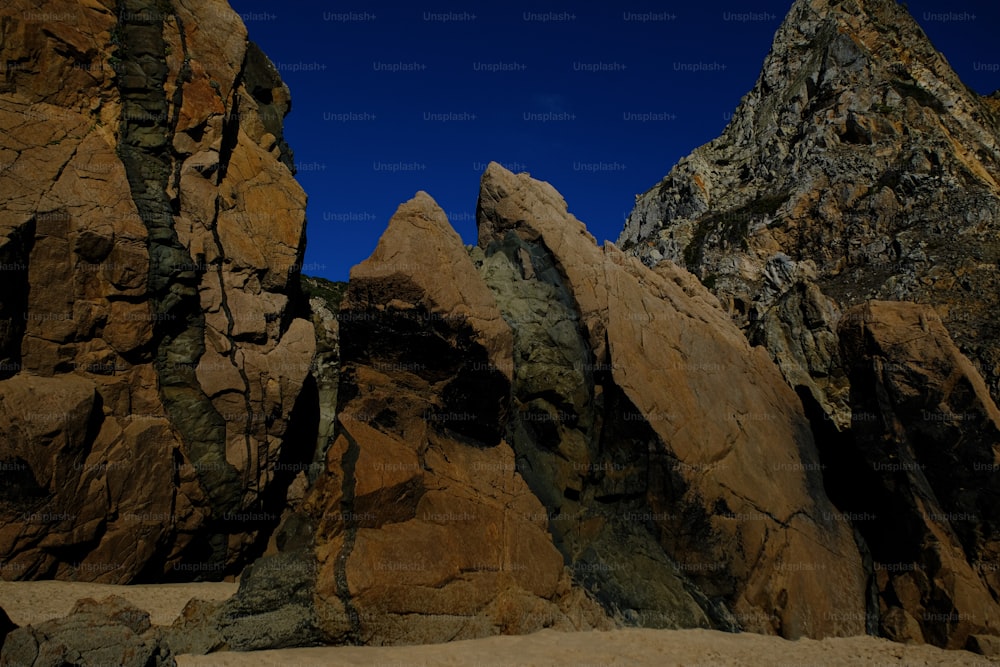 a group of rocks sitting on top of a sandy beach