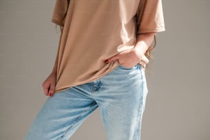 a woman wearing a tan shirt and blue jeans