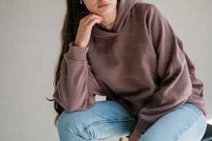 a woman sitting on a stool with her hand on her chin