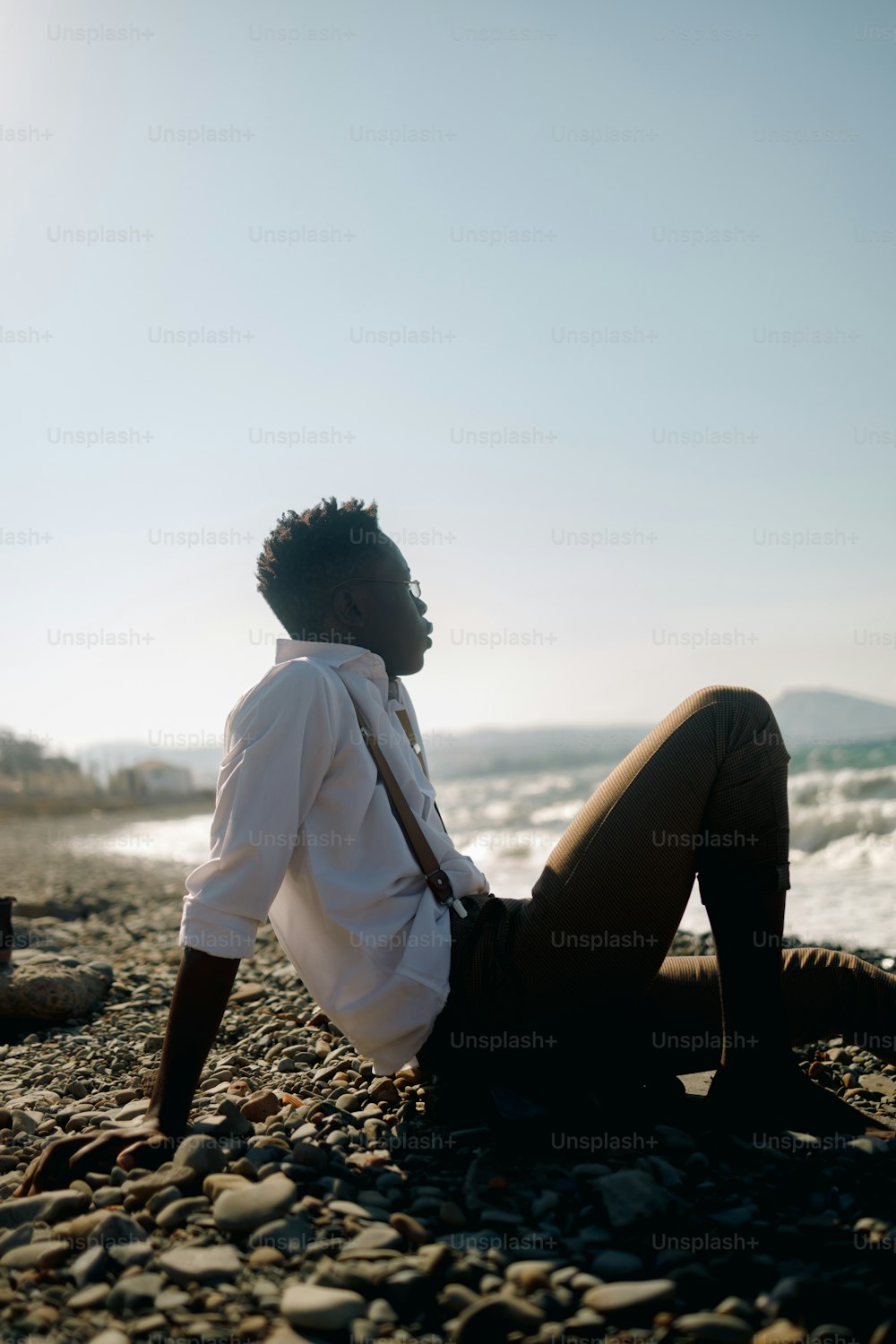 Ein Mann, der an einem felsigen Strand neben dem Meer sitzt