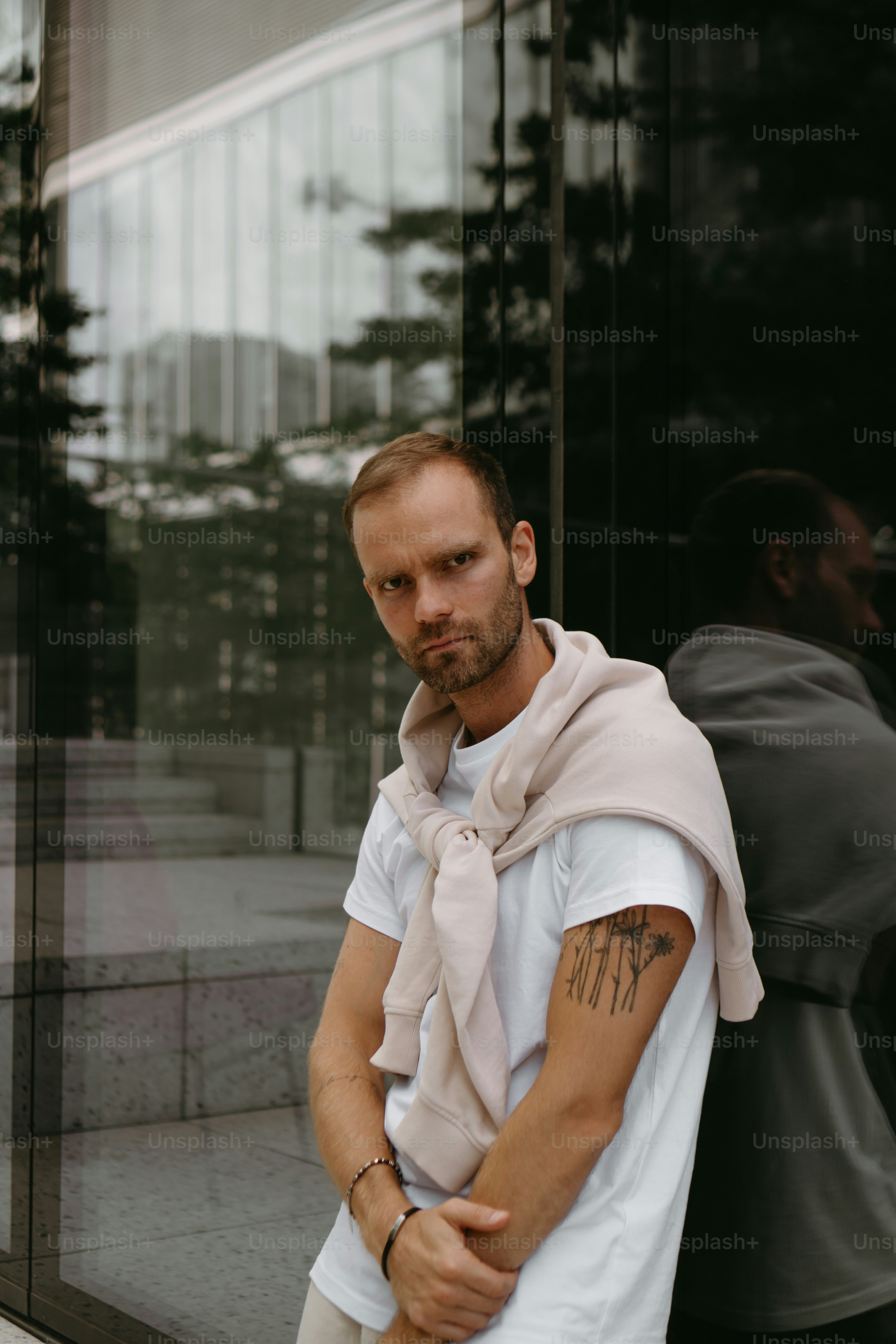 a man with a scarf around his neck leaning against a wall