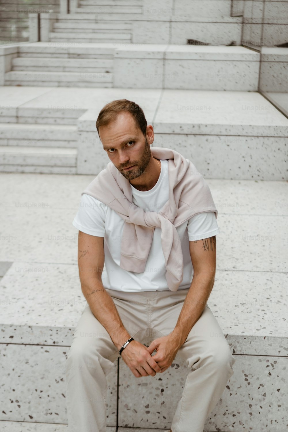 Un homme assis sur des marches avec un foulard autour du cou
