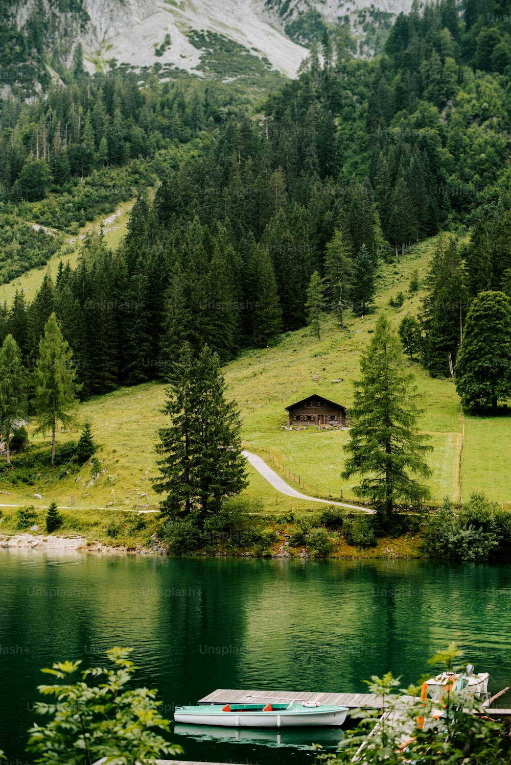 a boat sitting on top of a lake next to a lush green hillside