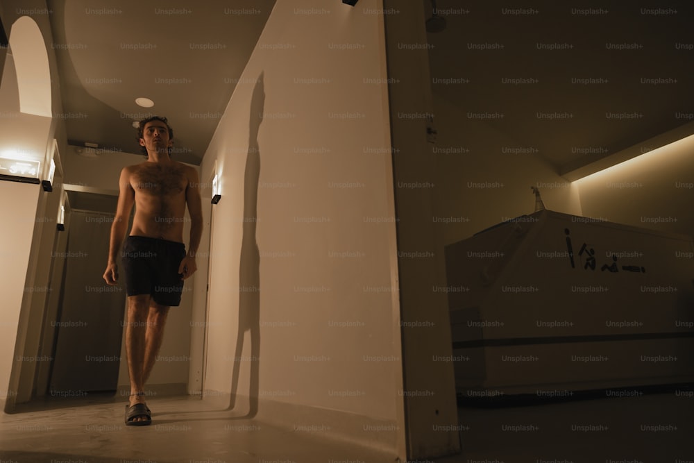 a shirtless man standing in a dimly lit room