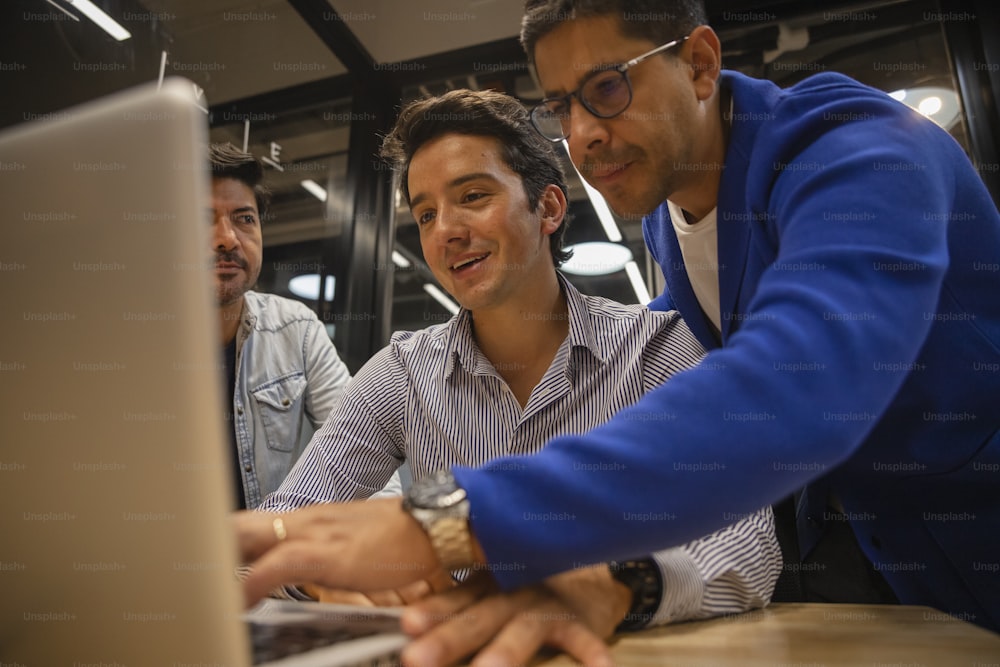 three men looking at a laptop screen together