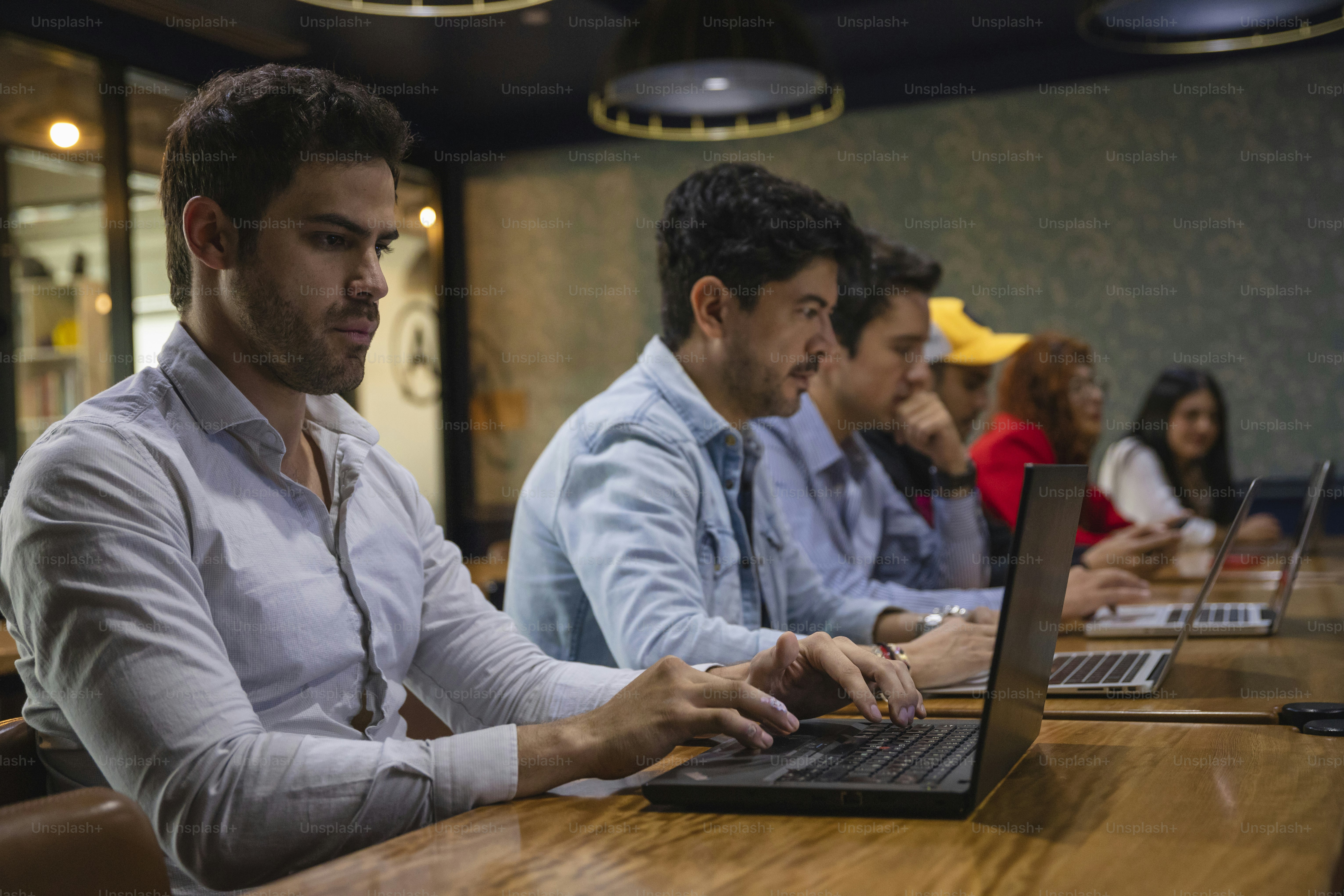 a group of people sitting at a table with laptops