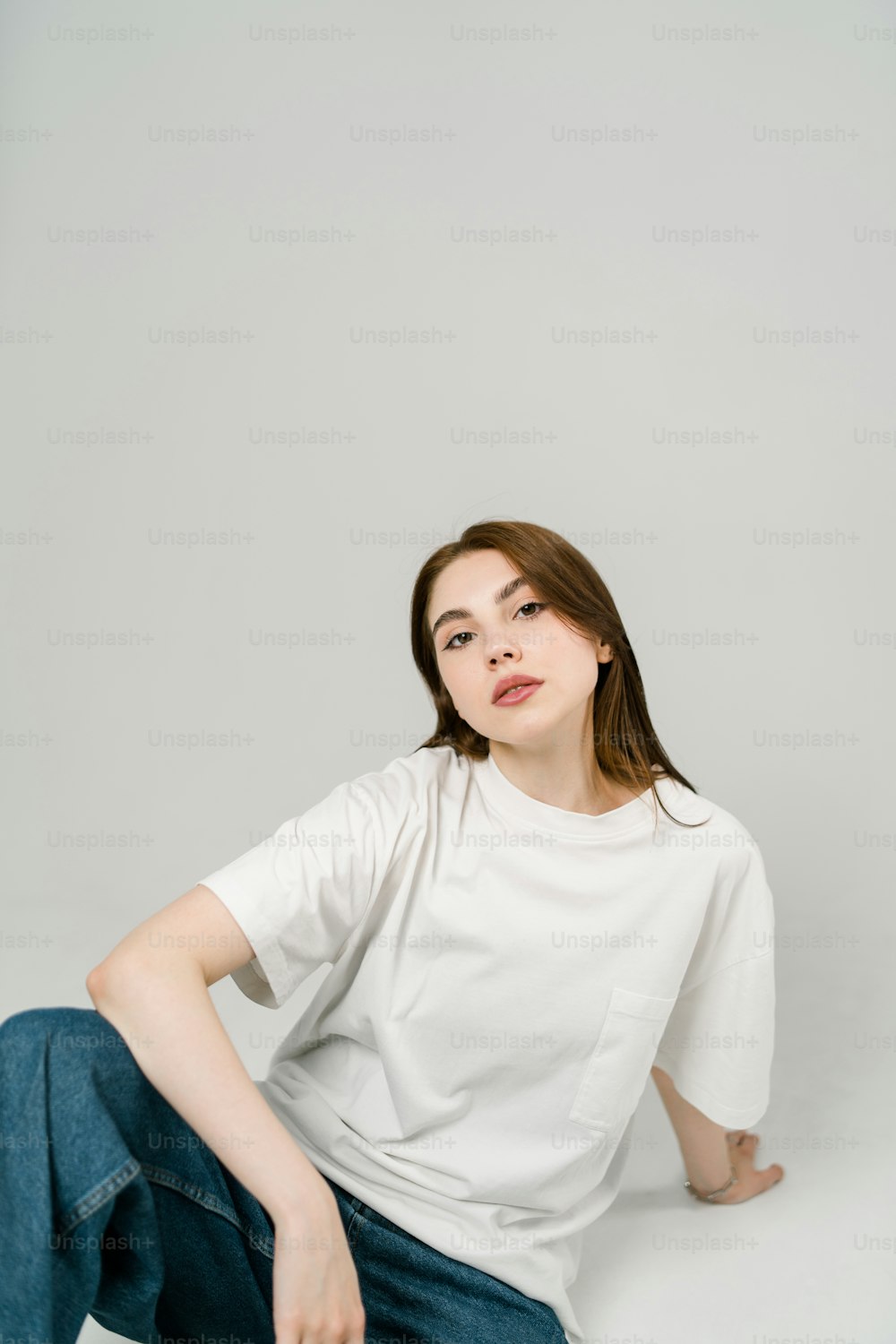 uma mulher sentada no chão vestindo uma camisa branca