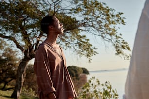 a man standing next to a tree near a body of water