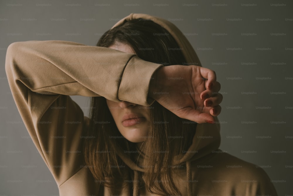 a woman in a brown hoodie covering her ears