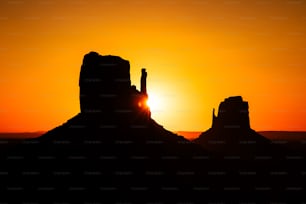 the sun is setting behind a mountain with a rock formation