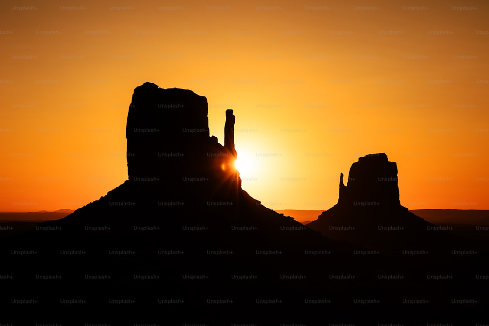 the sun is setting behind a mountain with a rock formation