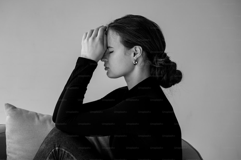 a black and white photo of a woman sitting on a couch