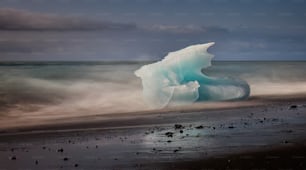 a large iceberg floating on top of a sandy beach