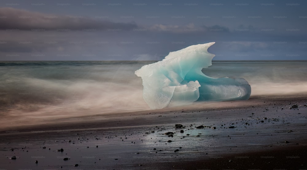 a large iceberg floating on top of a sandy beach