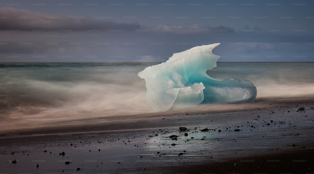 Un grand iceberg flottant au sommet d’une plage de sable