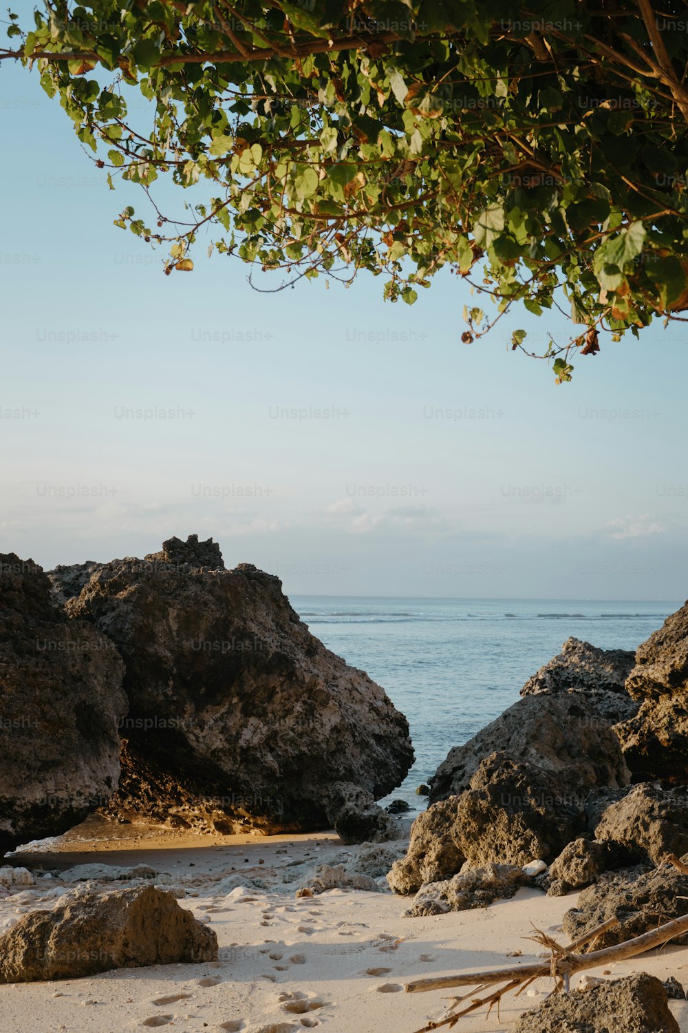 a sandy beach with rocks and water in the background