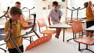 a group of young children standing around a room filled with desks